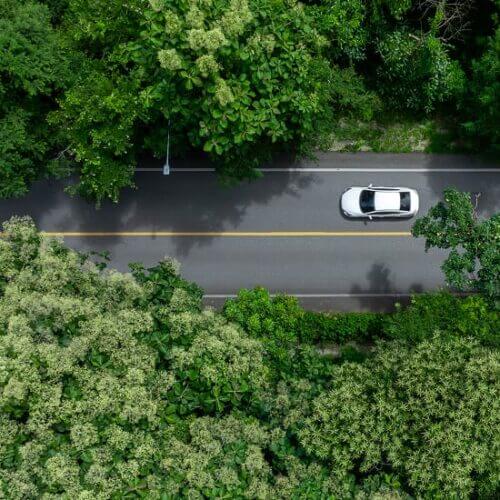 Looking down on a car driving down a road amid trees