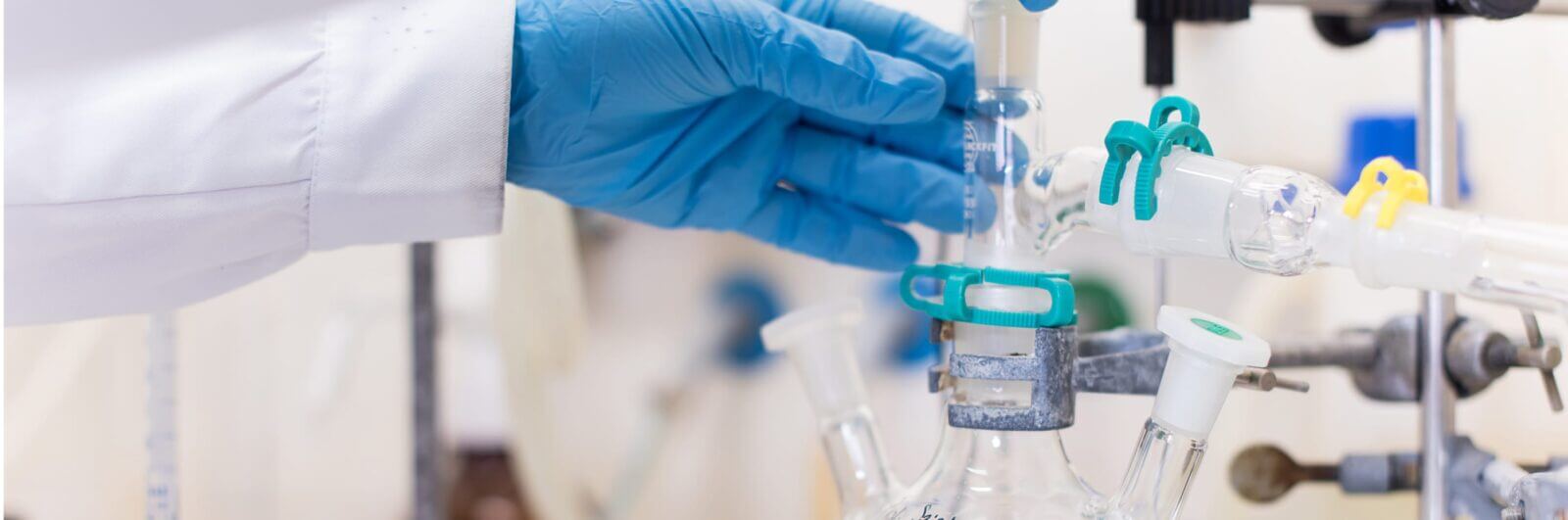 Gloved hands adjust a beaker in a lab
