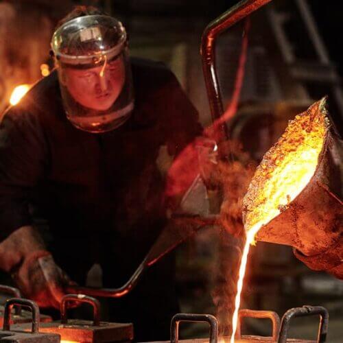 Worker pouring molten metal into a cast