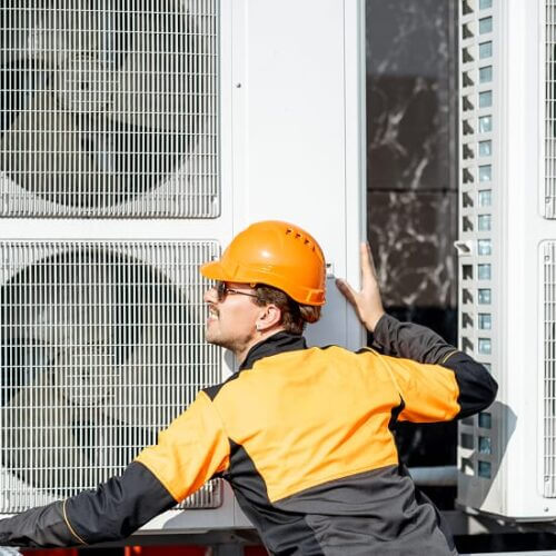 Worker installing air conditioning compressors