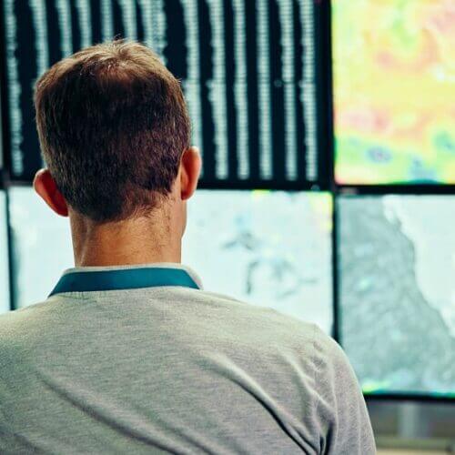 Employee watching a wall of screens displaying weather data
