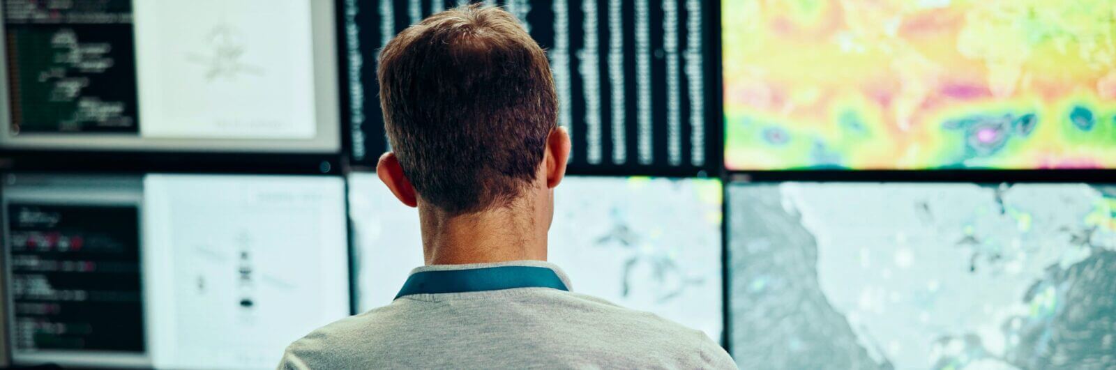 Employee watching a wall of screens displaying weather data